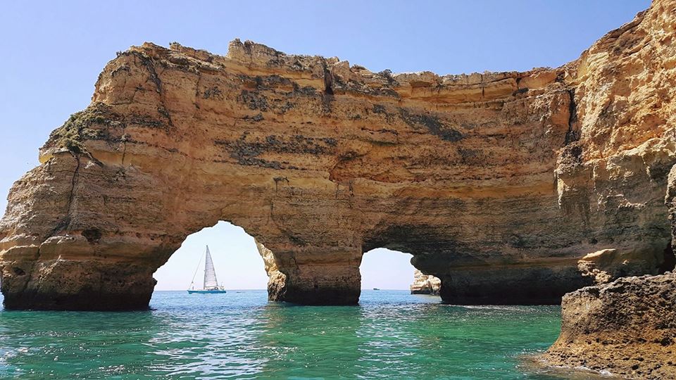 Sailboat passing through a rock arch near Carvoeiro and Benagil, Algarve