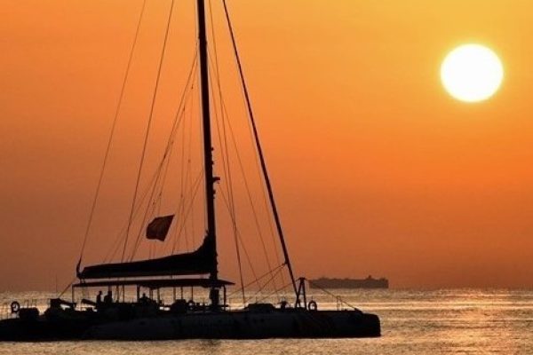 Catamaran enjoying a stunning orange sunset at sea in Valencia