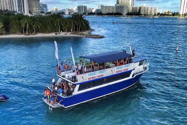 A large double-decker sightseeing boat cruising through the blue waters of Biscayne Bay Miami.