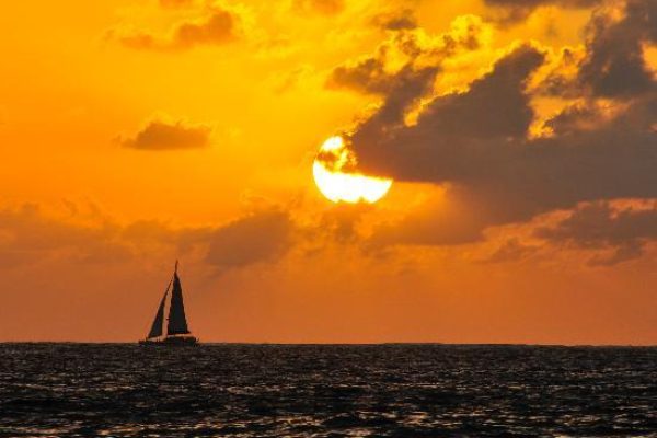 Sailing Catamaran sailing during a bright orange sunset in Hawaii