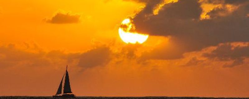 Sailing Catamaran sailing during a bright orange sunset in Hawaii