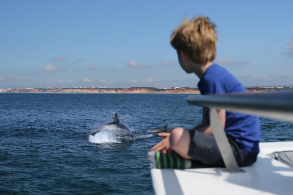 Kind op een boot dat wilde dolfijnen bekijkt in Vilamoura