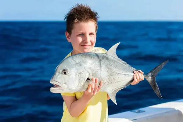 Chico con un pez en un tour de pesca en un arrecife en Vilamoura