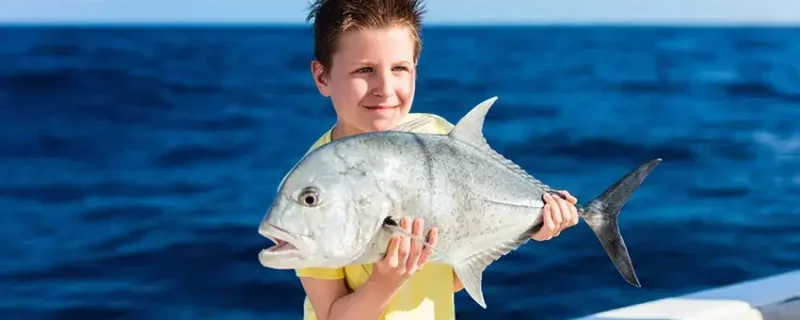 Chico con un pez en un tour de pesca en un arrecife en Vilamoura