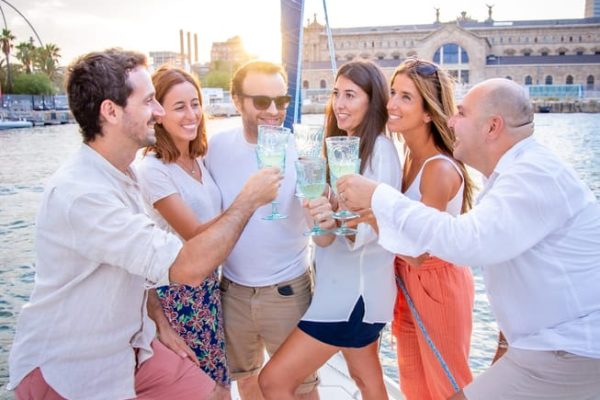 Feiernde Menschen mit Getränken auf einem Segelboot in Barcelona.